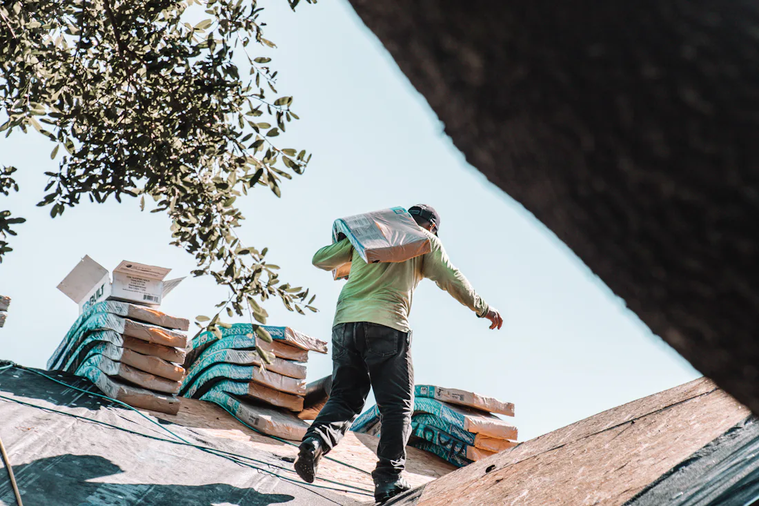 Roofer carrying shingles across a residential roof in Austin